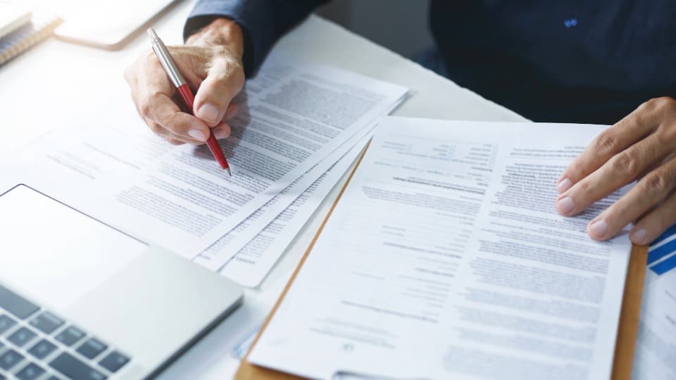 Person reviews customs documents at a desk with pen, forms and laptop, symbolizing UK to Germany customs